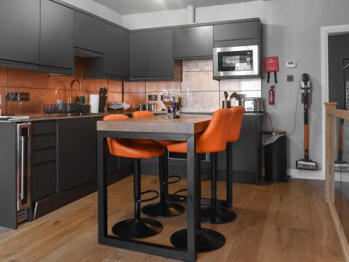 a kitchen with black cabinets and orange bar stools at The Copper Loft in Windermere