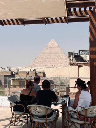 a group of people sitting at a table in front of the pyramid at LE Grand Pyramids View & Suites in Cairo