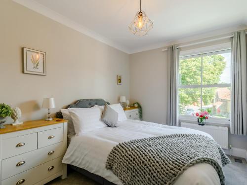 a bedroom with a bed with a dresser and a window at The Old Post Office in Baldersby