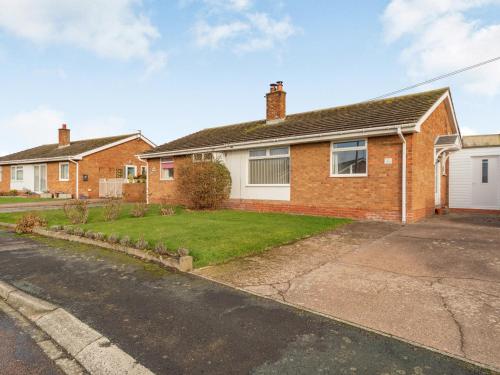 a brick house with a grass yard at Gan Hyem in Beadnell