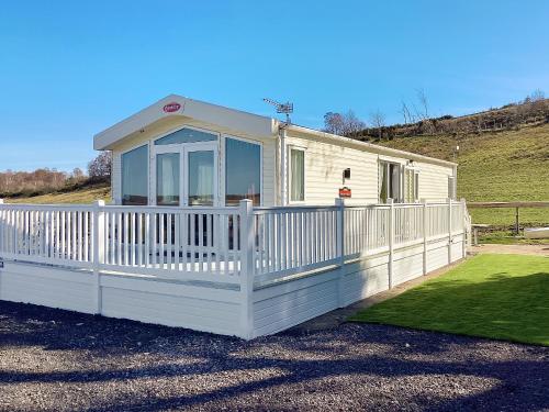 a small white house with a white fence at Ballagan Lodge in Leanach
