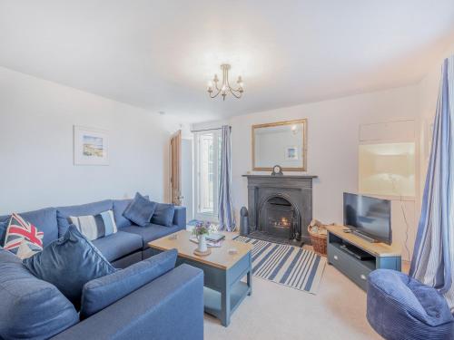 ein Wohnzimmer mit einer blauen Couch und einem Kamin in der Unterkunft Millhouse Cottage in Bamburgh