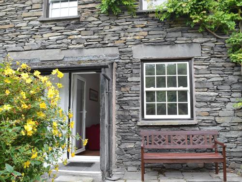 a bench sitting outside of a stone building with a window at Stockdale Cottage in Ambleside