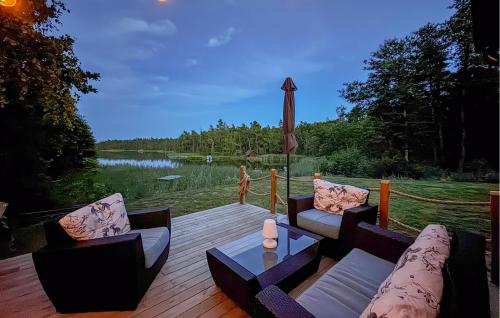 a deck with couches and a table with a view of a lake at Nice Home In Figeholm in Figeholm