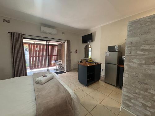 a bedroom with a bed and a kitchen with a refrigerator at 59 van Heerden in Mokopane