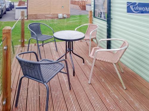 three chairs and a table on a deck at Regal Lodge in Plumbland