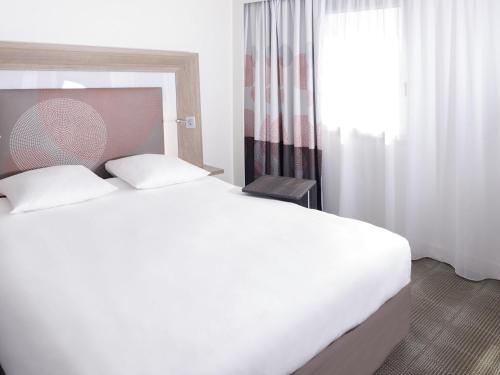 a bedroom with a large white bed and a window at Novotel Marseille Centre Prado Vélodrome in Marseille