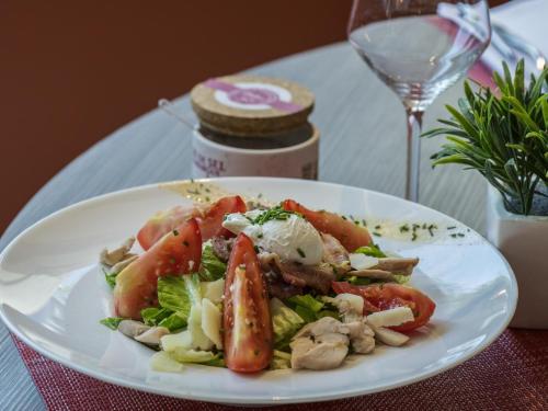 a white plate with a salad on a table with a wine glass at Novotel Marseille Centre Prado Vélodrome in Marseille