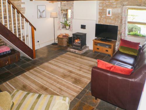 een woonkamer met een bank en een open haard bij Garden Cottage in Onecote