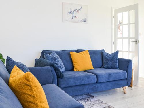 a blue couch with yellow pillows in a living room at Driftwood Cottage in Sewerby