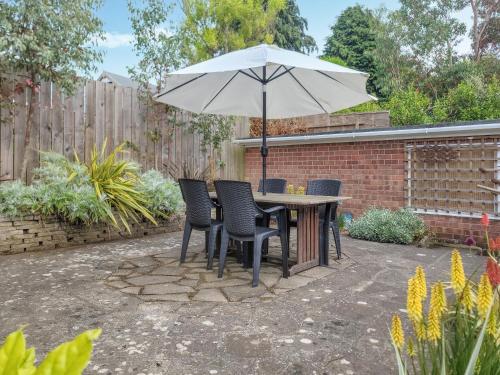 a patio with a table and chairs and an umbrella at Driftwood Cottage in Sewerby