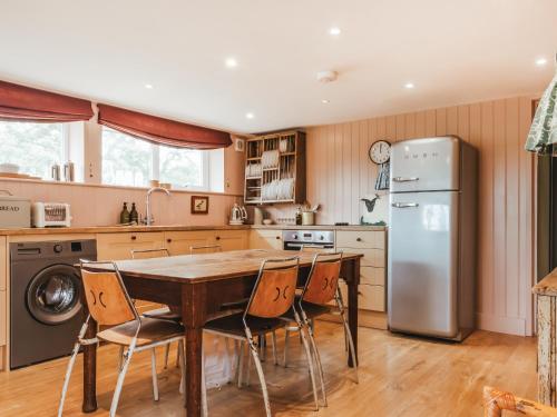 a kitchen with a wooden table and a refrigerator at The Shearing Shed in Peasmarsh