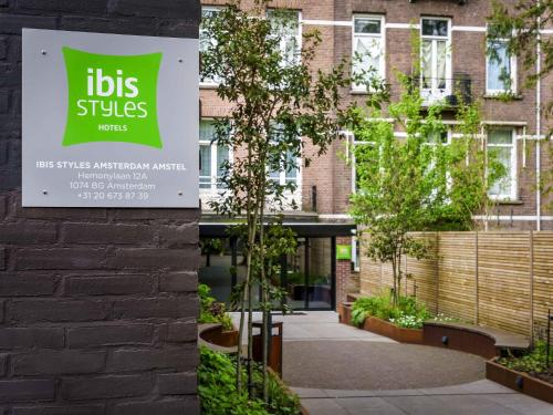 a sign on the side of a building with trees at ibis Styles Amsterdam Amstel in Amsterdam