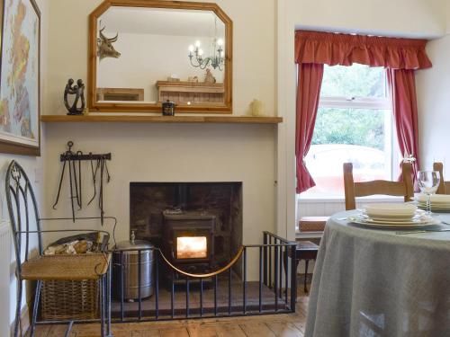 a living room with a fireplace and a table at Hill View House in Aberfeldy