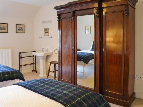 a bedroom with two beds and a cabinet with a mirror at Einich in Newtonmore
