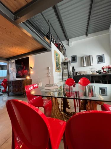 a dining room with red chairs and a glass table at LoftDesign in Verona