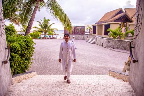 a man in a white suit walking down a street at Le Domaine de L'Orangeraie Resort and Spa in La Digue