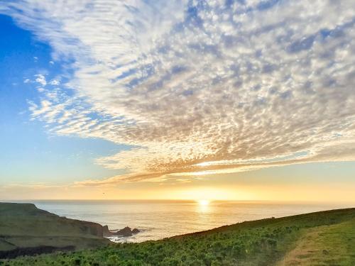 a sunset over the ocean with a cloudy sky at Puffin House - Uk46843 in Hartland