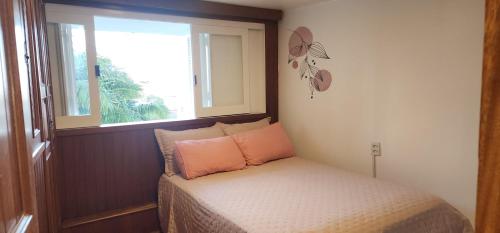 a small bedroom with a bed and a window at Apartamento Pé na Areia- Torres in Torres