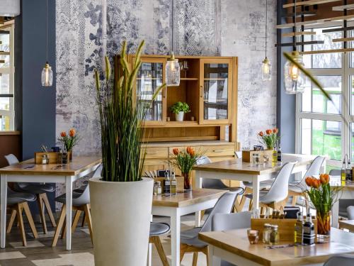 a restaurant with tables and chairs and plants at Ibis Styles Regensburg in Regensburg