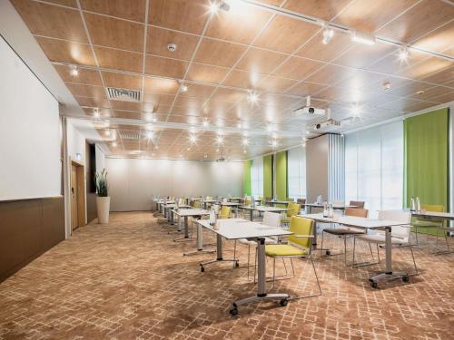 a conference room with tables and yellow chairs at Ibis Styles Regensburg in Regensburg