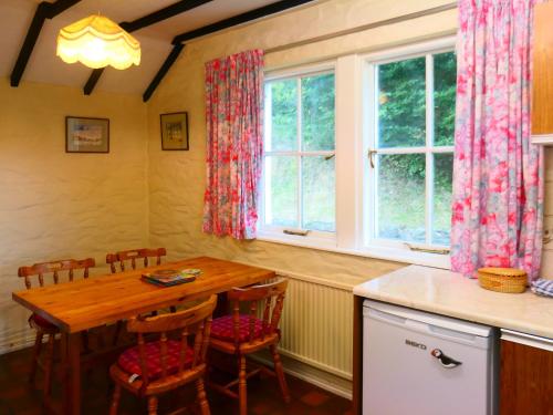 cocina con mesa de madera, sillas y ventana en Bridge Cottage, en Lockerbie