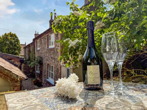 a bottle of wine and two glasses on a table at Forge Cottage in Stiffkey