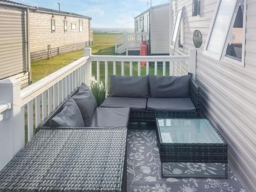a balcony with a couch and a glass table at Marni's Seaview in Heysham