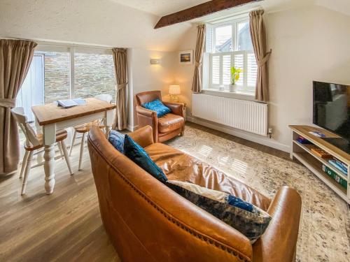 a living room with a leather couch and a table at Honeysuckle in Delabole
