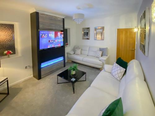 Una sala de estar con un sofá blanco y un televisor de pantalla plana. en Newcastle Lodges, en Thornton