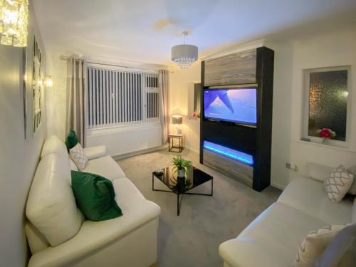 Una sala de estar con un sofá blanco y un televisor de pantalla plana. en Newcastle Lodges, en Thornton