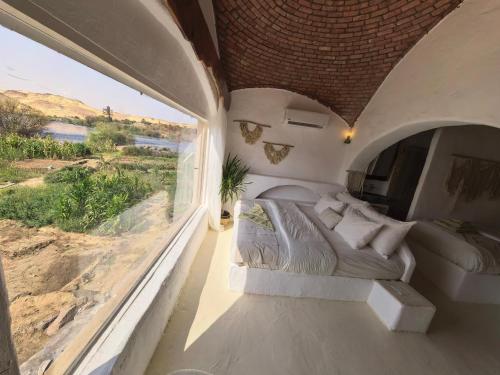 a bedroom with a bed and a large window at Nala Narty Boutique Hotel & Farm in Aswan