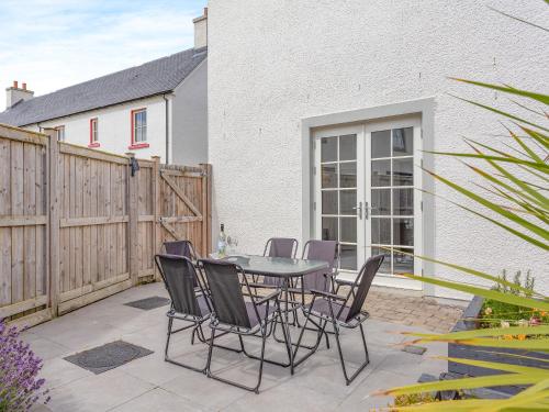 a patio with a table and chairs and a fence at One The Loan in Croy