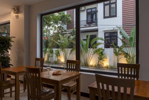 a dining room with a table and chairs and a large window at Sunora Villa Hoi An in Hoi An