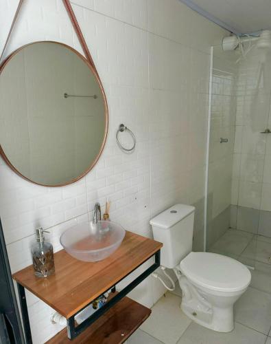 a bathroom with a sink and a toilet and a mirror at Mini Casa Privativa -Praia do Tombo in Guarujá