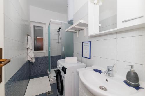 a bathroom with a sink and a washing machine at Beach House Kocer in Pirovac