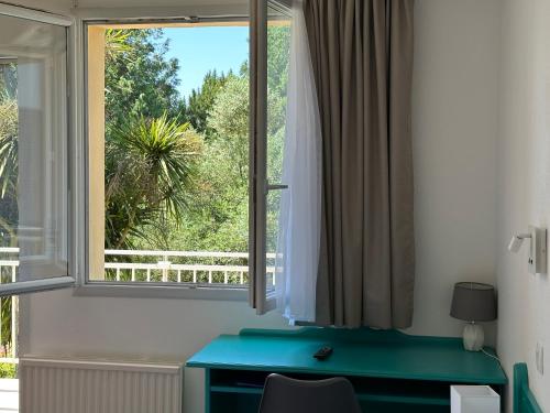 a room with a blue desk and a window at Logis Hôtel La Demeure du Perron in Quettehou