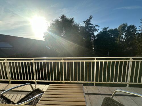a sun is shining over a white fence at Logis Hôtel La Demeure du Perron in Quettehou