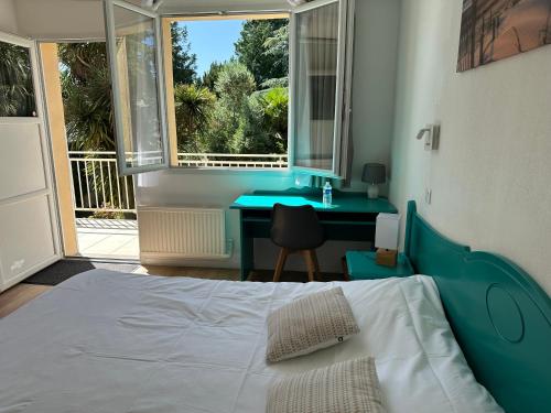 a bedroom with a bed and a desk and a window at Logis Hôtel La Demeure du Perron in Quettehou