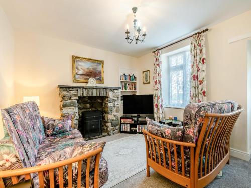 a living room with two chairs and a fireplace at Stybarrow View Cottage in Glenridding