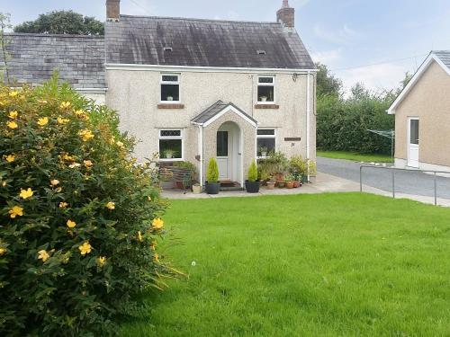 a house with a green yard with flowers in front of it at Tirmynydd Farm Cottage in Dunvant