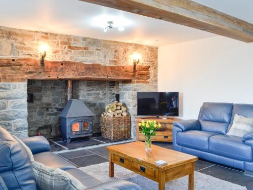 a living room with couches and a stone fireplace at Pistyll Gwyn in Llanwrthwl