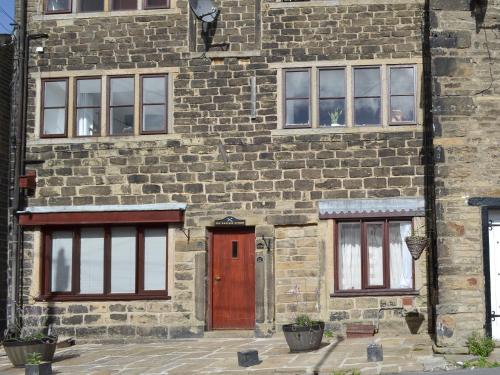 a brick building with a brown door and two windows at Weavers Houses - Uk12796 in Hayfield