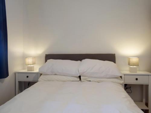 a bed with white sheets and two nightstands with lamps at Red Kite Lodge - Uk32610 in Old Radnor