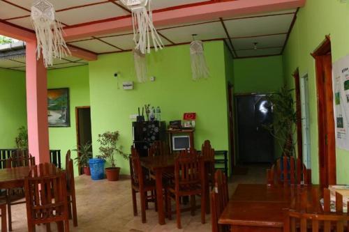 a restaurant with green walls and wooden tables and chairs at Little heaven guest in Ella