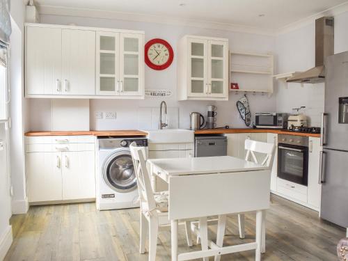 a kitchen with white cabinets and a table and chairs at Puffin Cottage in Amble