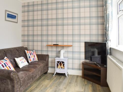 a living room with a couch and a fireplace at Puffin Cottage in Amble