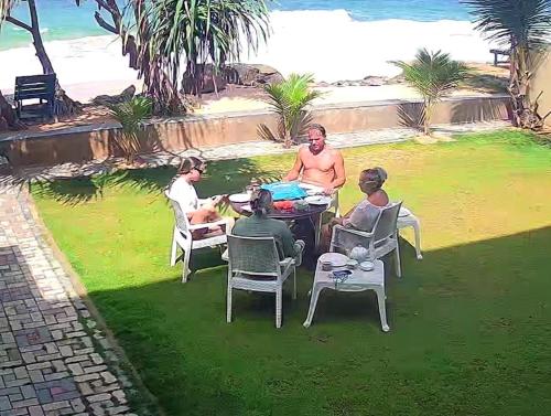 a group of people sitting around a table near the beach at Blue Wave Beach Villa by Aaryan Group in Ambalangoda