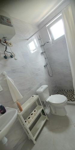 a white bathroom with a toilet and a sink at Residência Alto Saco, Double room with private bathroom in Tarrafal