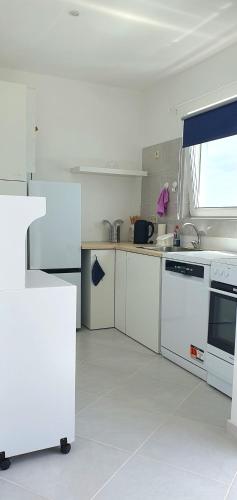 a white kitchen with white appliances and a window at Residência Alto Saco, Double room with private bathroom in Tarrafal